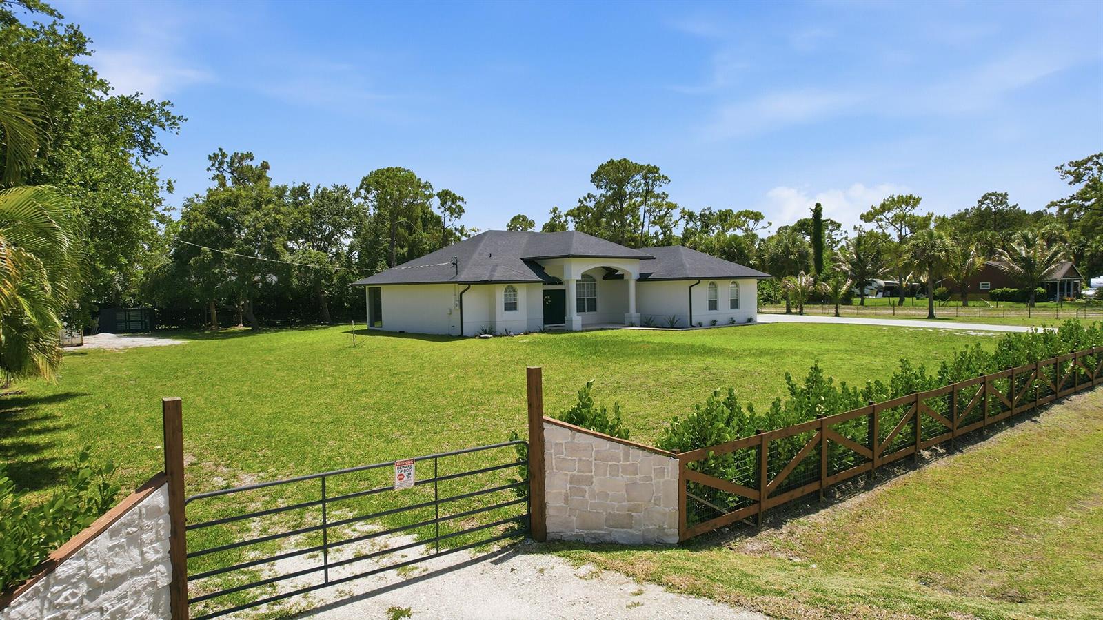 A white single-story house with a dark roof sits on a large grassy lot — 18220 N 90th St Street N, FL 33470, FL