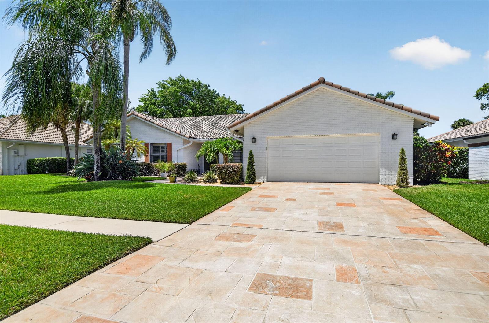 A white brick house with a tiled roof and a patterned driveway sits on a lawn — 10221 Harbourtown Court, Boca Raton FL 33498, BOCA RATON, FL