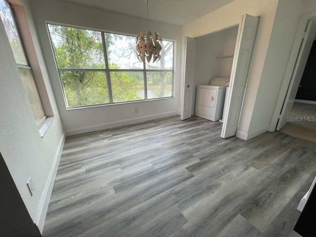 A room with wood-look flooring, a large window, a hanging light fixture, and laundry closet — 5140 CONROY ROAD UNIT 37, ORLANDO, FL