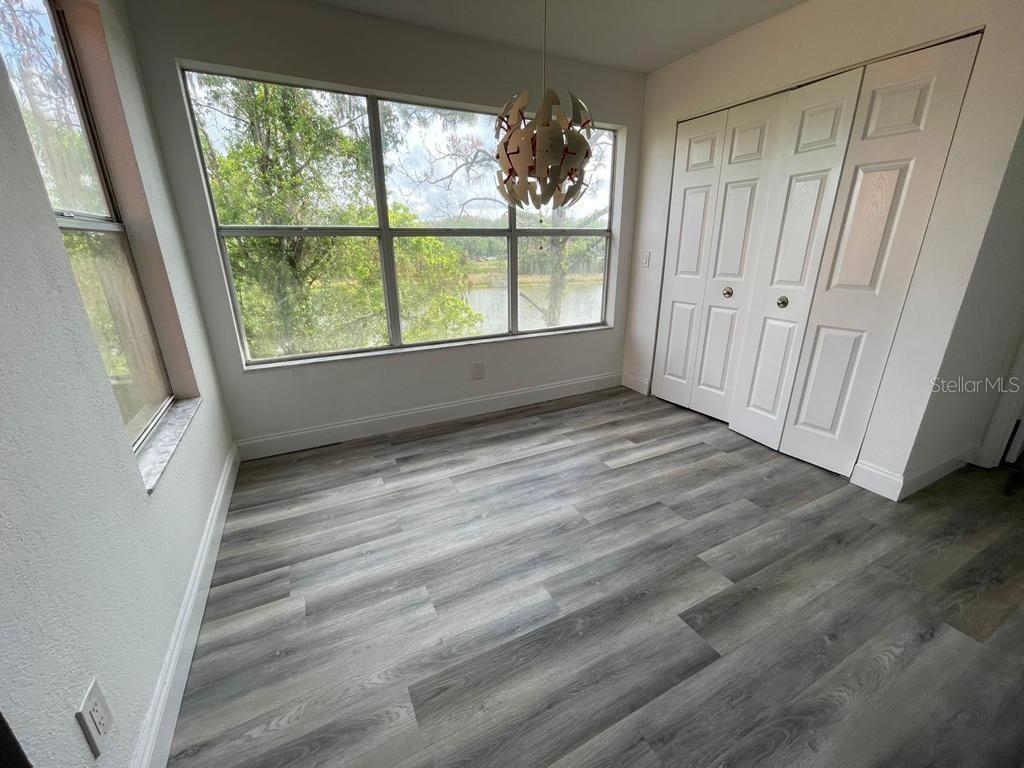 A room with wood-look flooring, a large window overlooking a lake, and white closet doors — 5140 CONROY ROAD UNIT 37, ORLANDO, FL