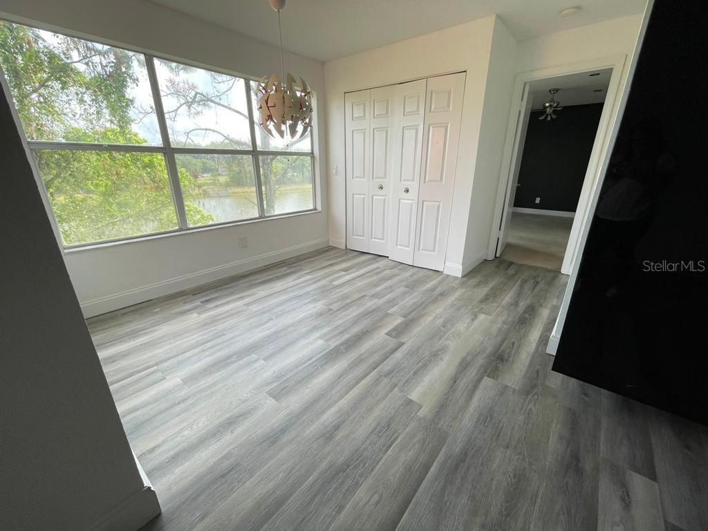 A dining area features light wood-look flooring, a large window, and white bifold closet doors — 5140 CONROY ROAD UNIT 37, ORLANDO, FL