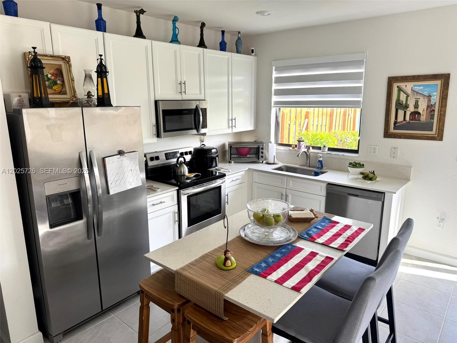 A kitchen features white cabinets, stainless steel appliances, a center island, and a window — 10020 SW 228th Ter, Miami FL 33190, MIAMI, FL