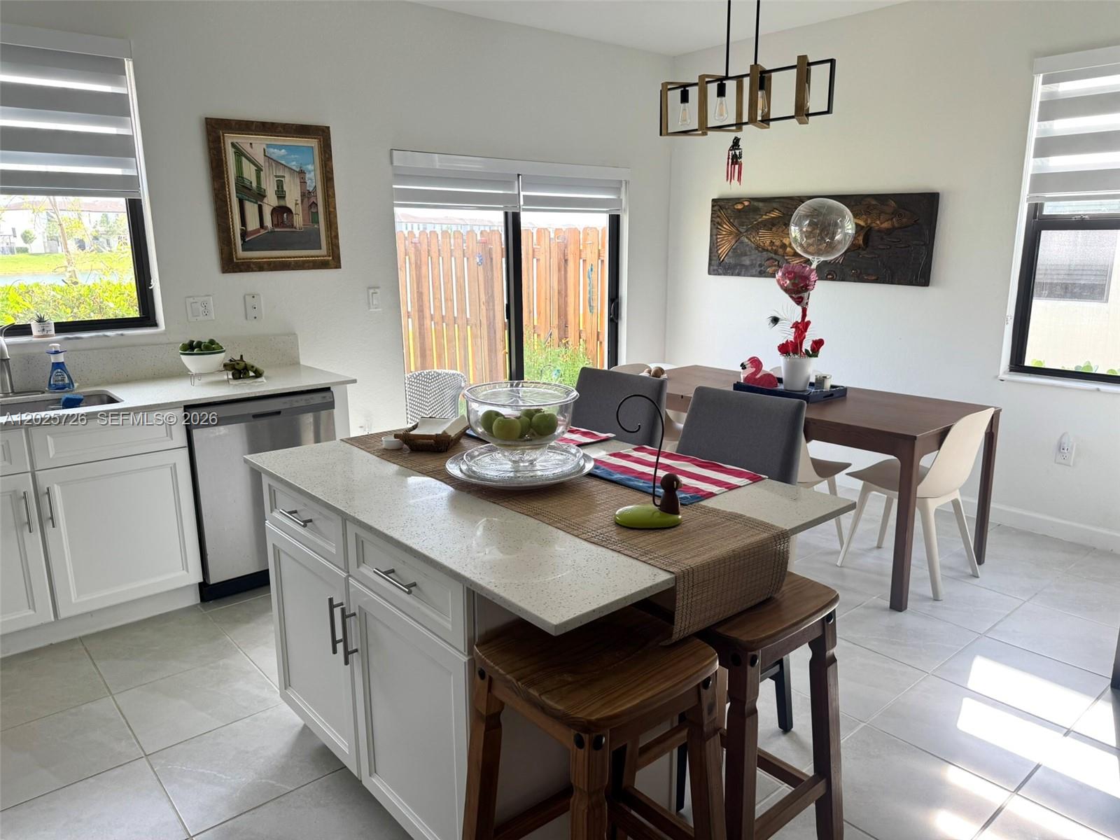 A kitchen with a white island, wooden stools, and an adjacent dining area — 10020 SW 228th Ter, Miami FL 33190, MIAMI, FL