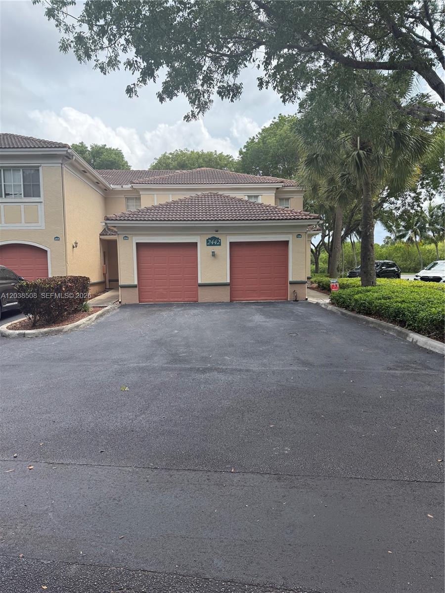A two-story residential building features two red garage doors and a paved driveway — 2442 Centergate Dr # 206, Miramar FL 33025, MIRAMAR, FL