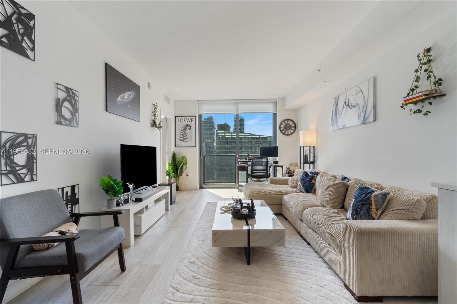A modern living room features a beige sectional sofa, a marble coffee table, and city views — 55 SW 9th St # 3005, Miami FL 33130, MIAMI, FL