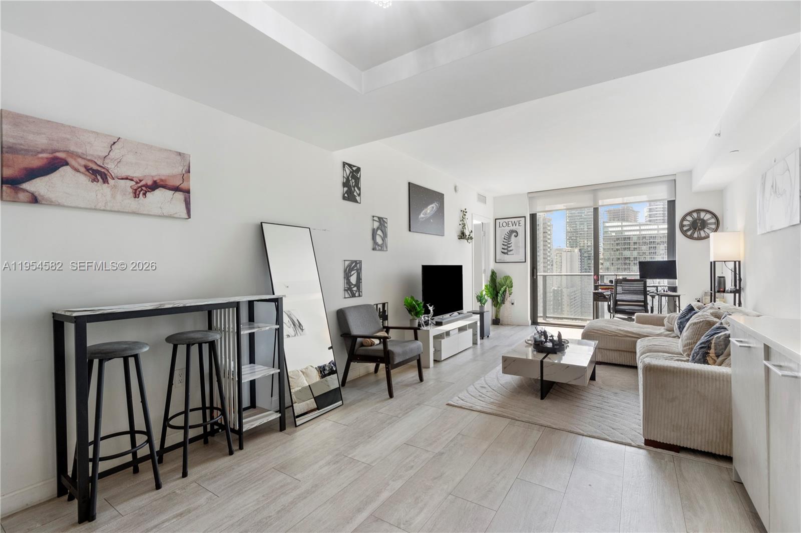 A modern living room features a sofa, television, dining table, and floor-to-ceiling windows with city views — 55 SW 9th St # 3005, Miami FL 33130, MIAMI, FL