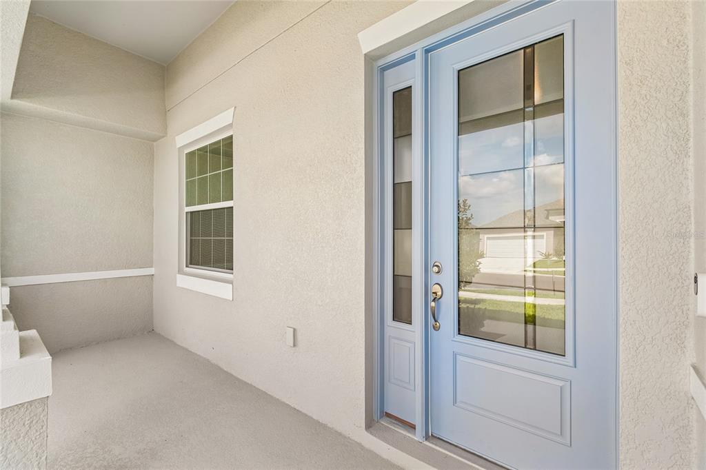 A light blue front door with glass panels sits on a covered concrete porch — 12610 KELLY ANN LOOP, BROOKSVILLE, FL