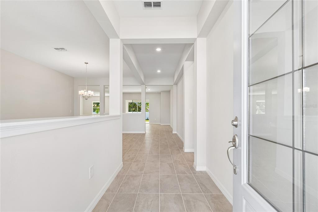 A bright entryway with tile flooring leads into an open-concept living area with white walls — 12610 KELLY ANN LOOP, BROOKSVILLE, FL