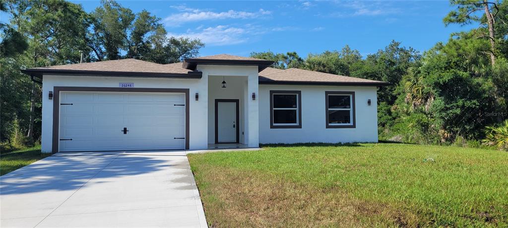 A single-story house with a white stucco exterior, brown trim, and a two-car garage — 26248 EAGER ROAD, PUNTA GORDA, FL