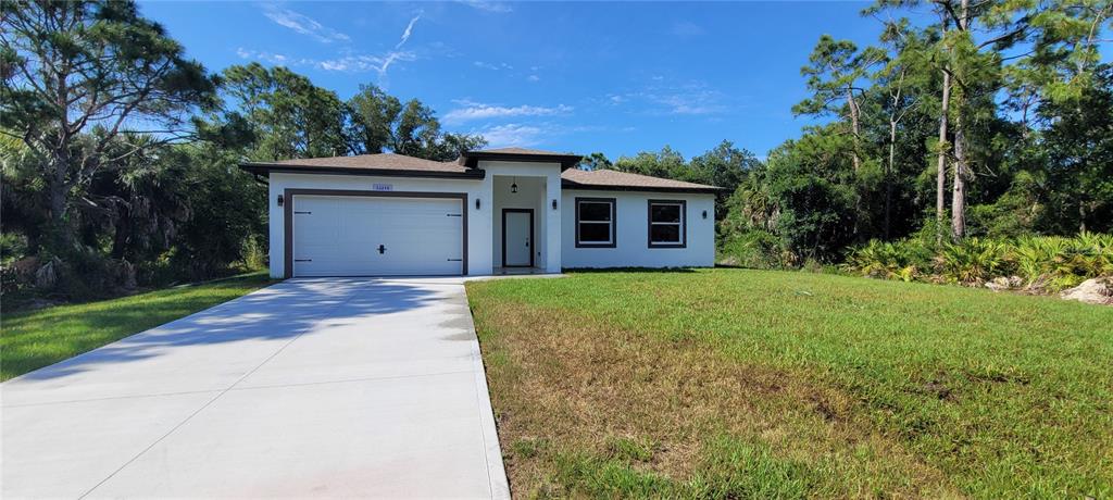 A single-story house with a white exterior, a two-car garage, and a concrete driveway — 26248 EAGER ROAD, PUNTA GORDA, FL