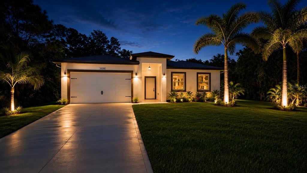 A single-story house with a white exterior, two-car garage, and palm trees at twilight — 26248 EAGER ROAD, PUNTA GORDA, FL