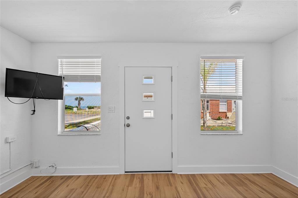 A room with white walls, wood-look flooring, a front door, and two windows — 908 VILLAS DRIVE UNIT 31, VENICE, FL