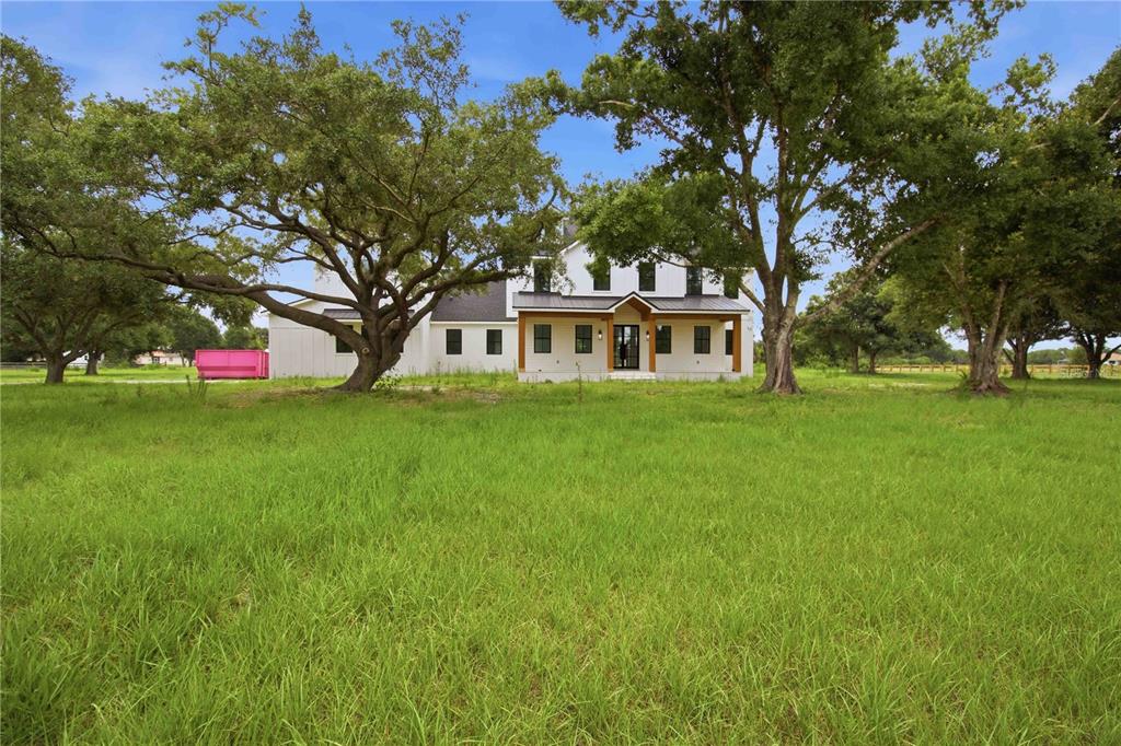 A white two-story farmhouse with a wooden porch sits in a large, grassy field — 639 OAKFORD ROAD, SARASOTA, FL