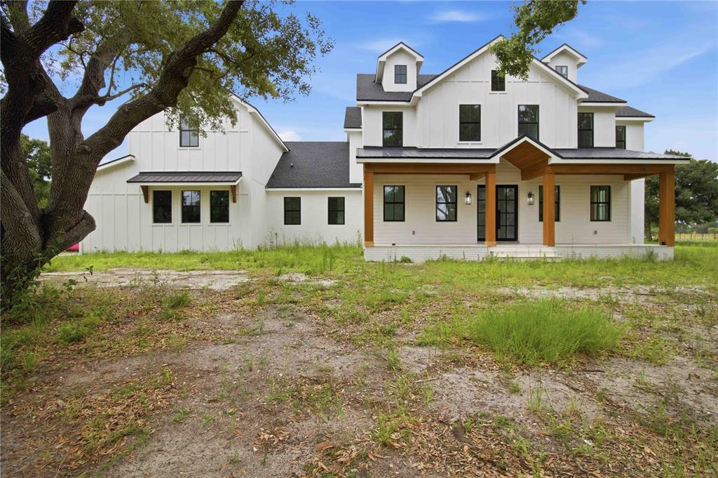 A two-story white farmhouse with a dark roof and a wooden front porch — 639 OAKFORD ROAD, SARASOTA, FL