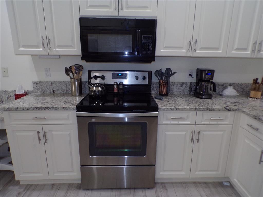 A kitchen features white cabinets, granite countertops, and stainless steel appliances — 3845 ALBACETE CIRCLE UNIT 50, PUNTA GORDA, FL