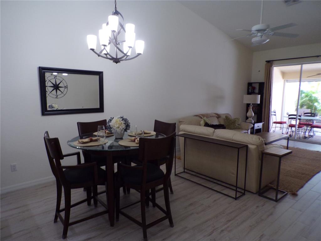 A dining area with a glass table and chandelier sits adjacent to a living room — 3845 ALBACETE CIRCLE UNIT 50, PUNTA GORDA, FL