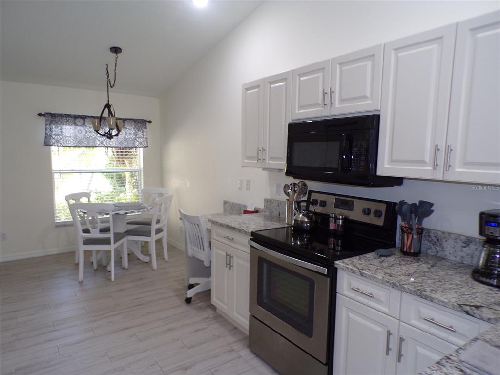 A kitchen features white cabinets, granite countertops, stainless steel appliances, and an adjacent dining area — 3845 ALBACETE CIRCLE UNIT 50, PUNTA GORDA, FL