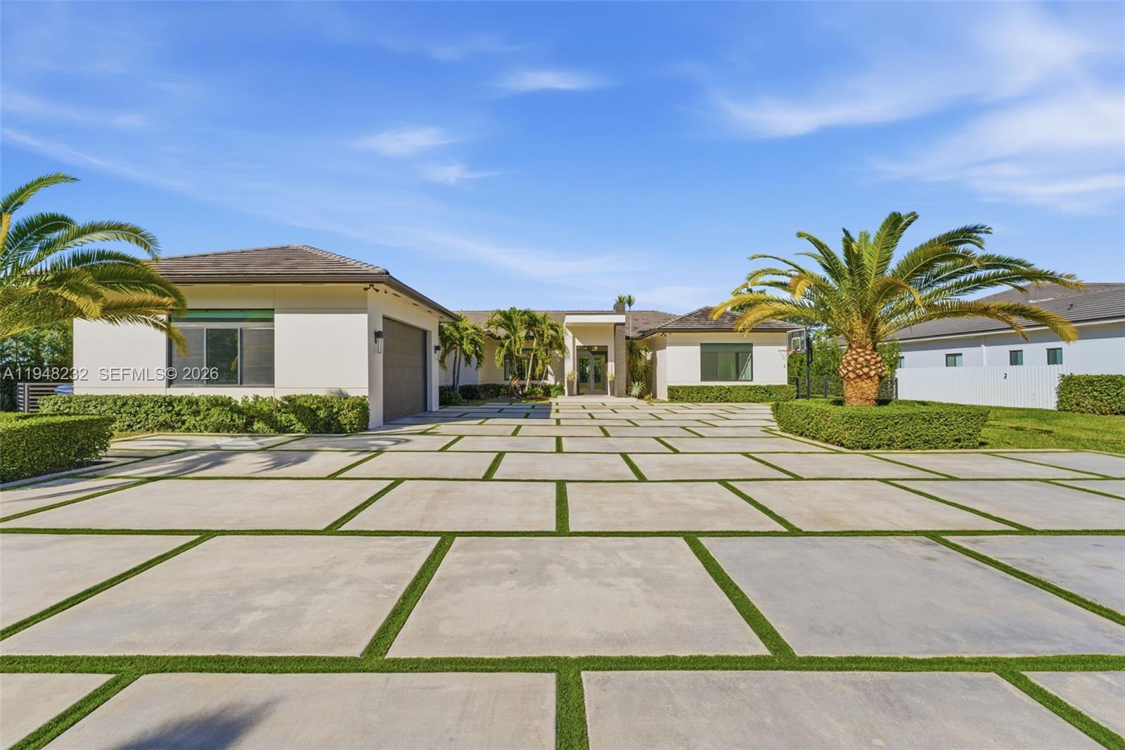 A gated driveway leads to a modern house flanked by two large palm trees — 10005 SW 66th St, Miami FL 33173, MIAMI, FL