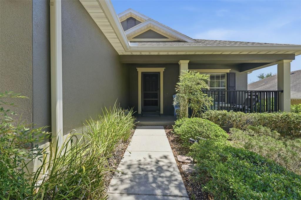 A concrete walkway leads to the covered front porch of a gray house — 20831 SULLIVAN RANCH BOULEVARD, MOUNT DORA, FL