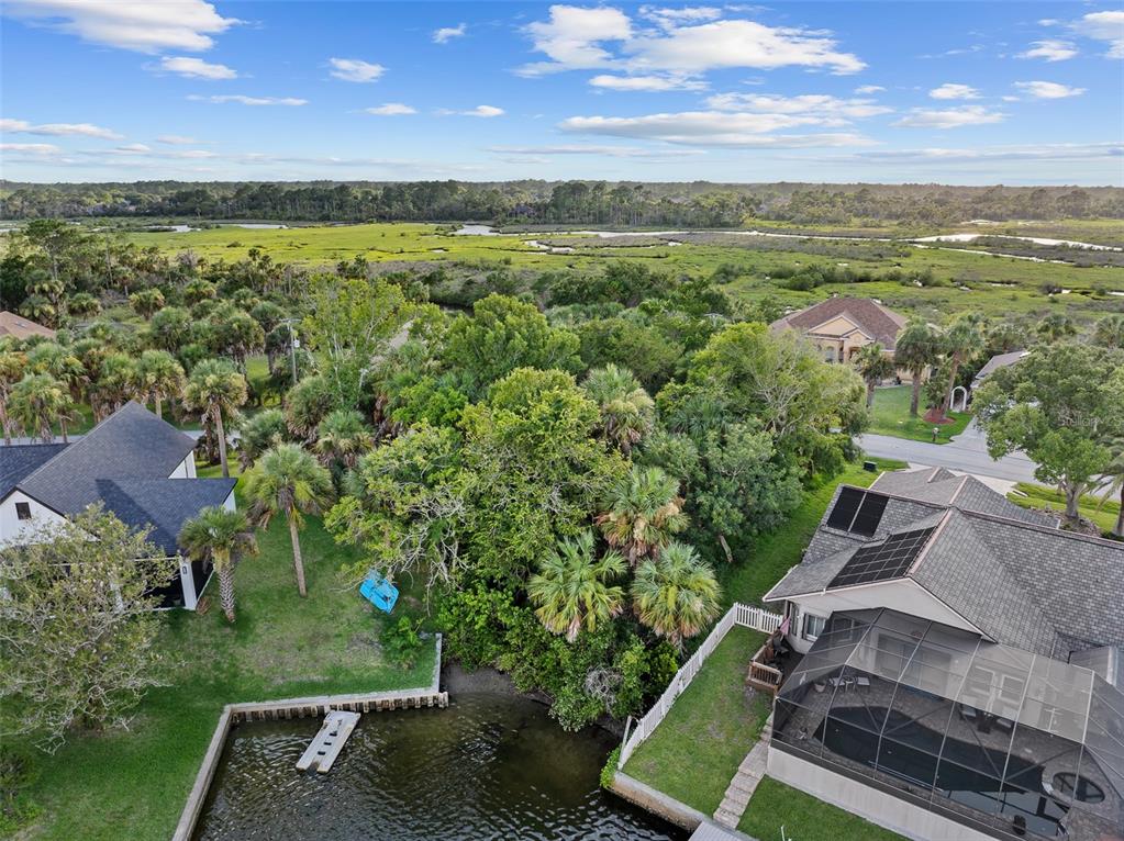 An aerial view shows a vacant, tree-covered lot outlined in red next to a canal — 14 COCHISE COURT, PALM COAST, FL