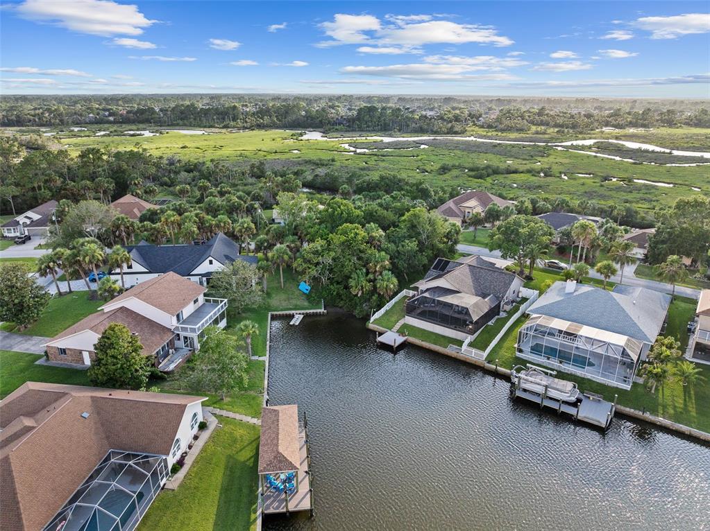 An aerial view shows two waterfront houses with docks separated by a dense wooded area — 14 COCHISE COURT, PALM COAST, FL