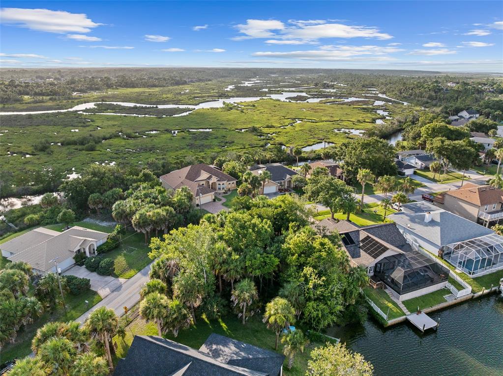 An aerial view shows waterfront houses with pools and private docks along a canal — 14 COCHISE COURT, PALM COAST, FL