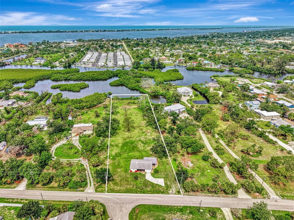 An aerial view shows a rectangular lot with a house, surrounded by trees and water — 780 S OXFORD DRIVE, ENGLEWOOD, FL