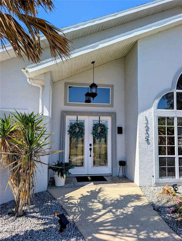 The exterior of a house features a white facade, double front doors, and a palm tree — 1235 E HARTFORD STREET, HERNANDO, FL