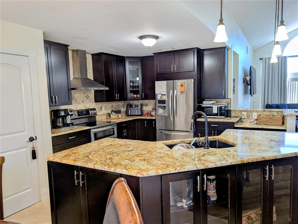 A kitchen features dark wood cabinets, granite countertops, stainless steel appliances, and a center island — 1235 E HARTFORD STREET, HERNANDO, FL