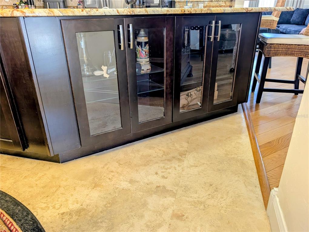 A kitchen island features dark wood cabinetry with glass-front doors and a stone countertop — 1235 E HARTFORD STREET, HERNANDO, FL