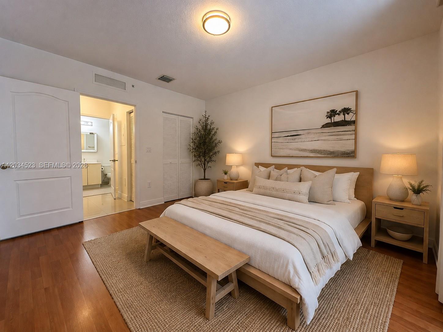 A bedroom features a wooden bed frame, a bench, and an attached bathroom — 652 NE 63rd St # 105, Miami FL 33138, MIAMI, FL