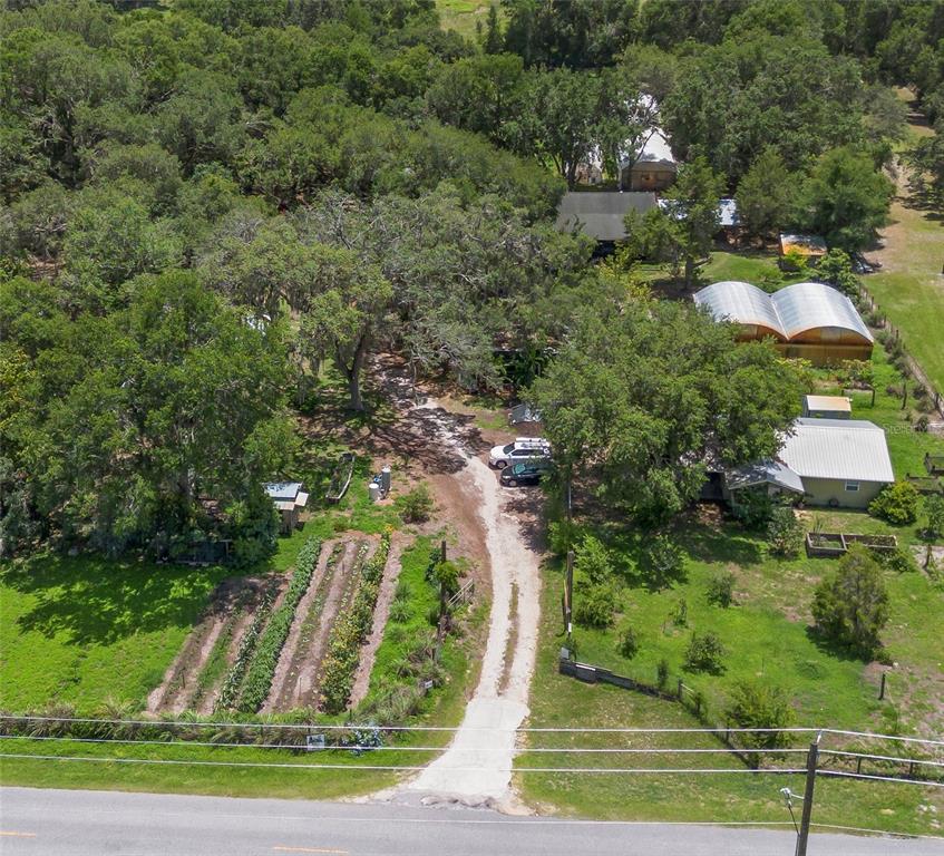 A single-story house with a screened porch sits under a large oak tree — 2026 LEWIS ROAD, LEESBURG, FL