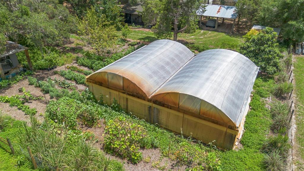 An aerial view shows a rural property with a house, greenhouse, and garden plots — 2026 LEWIS ROAD, LEESBURG, FL