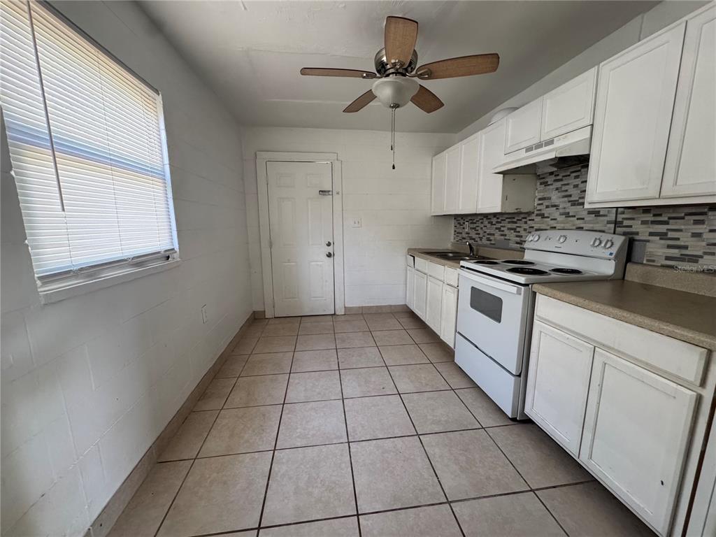 A kitchen features white cabinets, a white stove, tiled floors, and a ceiling fan — 1715 1/2 MARTIN LUTHER KING JR BOULEVARD, BARTOW, FL