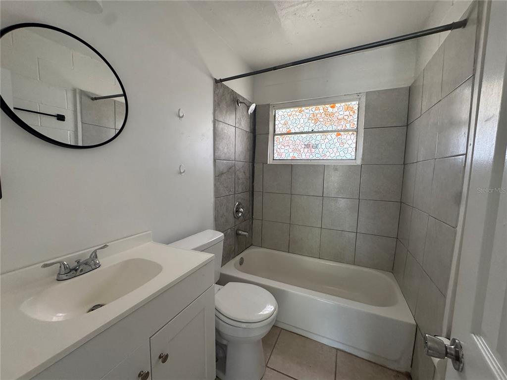 A bathroom features a white vanity, a toilet, and a tiled bathtub shower combination — 1715 1/2 MARTIN LUTHER KING JR BOULEVARD, BARTOW, FL