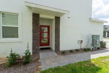 A front exterior view of a house featuring a red door and stone accents — 989 SPLASH SHOT PLACE UNIT ., DAVENPORT, FL