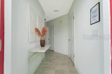 A hallway with light gray walls, tile flooring, a wall-mounted console table, and framed artwork — 989 SPLASH SHOT PLACE UNIT ., DAVENPORT, FL