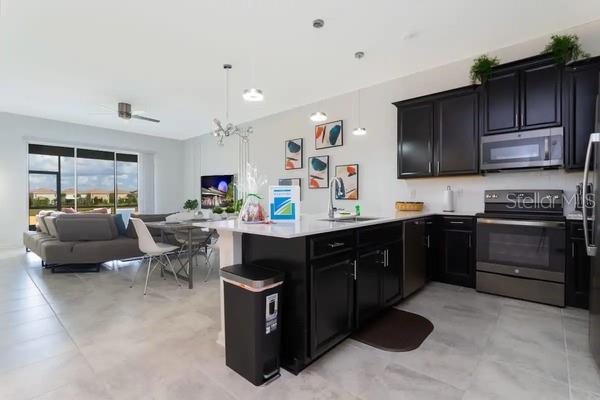 A modern open-concept kitchen with dark cabinets and a white island overlooks a living area — 989 SPLASH SHOT PLACE UNIT ., DAVENPORT, FL