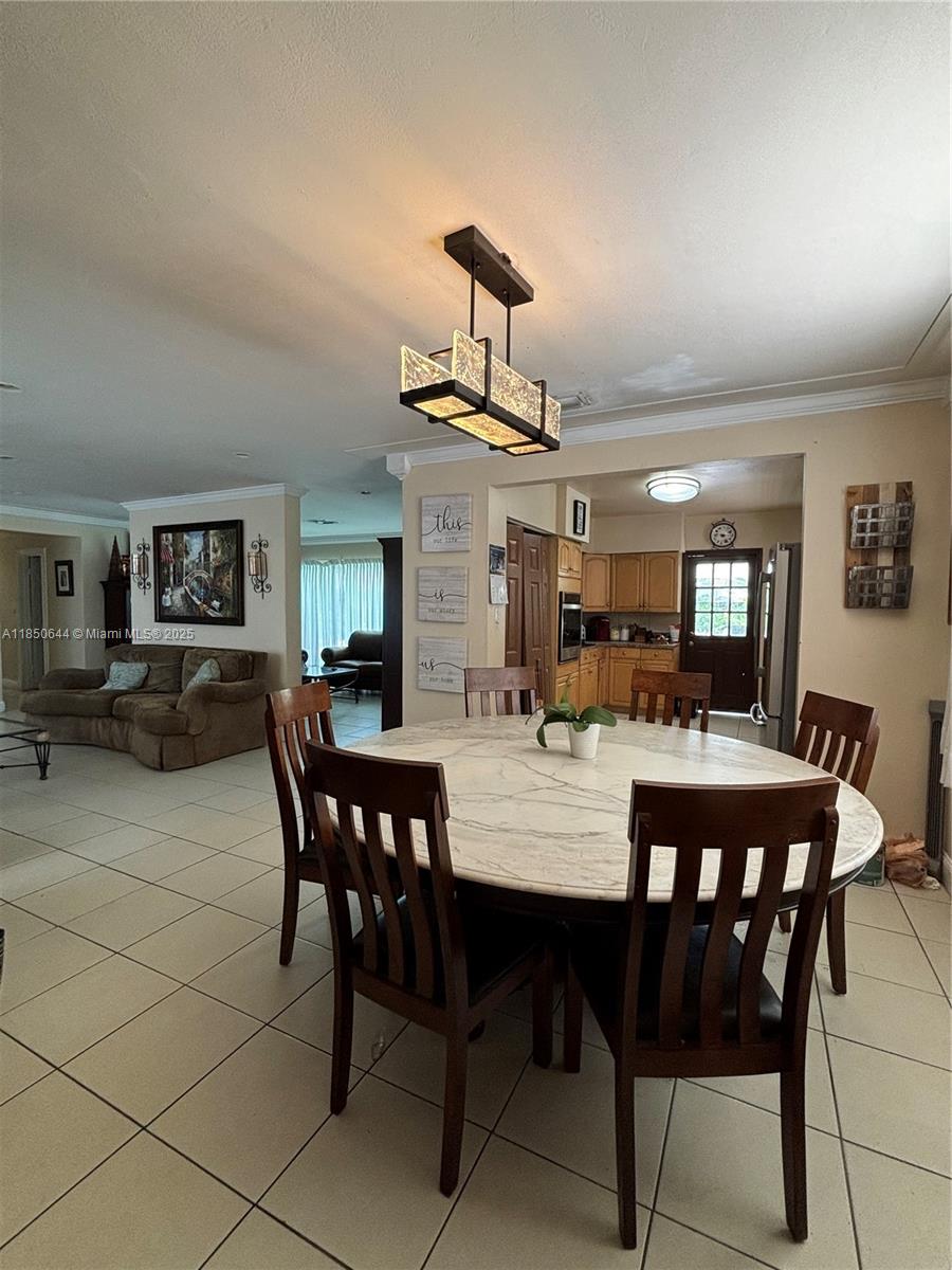 A dining area with a round marble table and chairs sits adjacent to a kitchen — 6440 Miller Dr, South Miami FL 33155, SOUTH MIAMI, FL