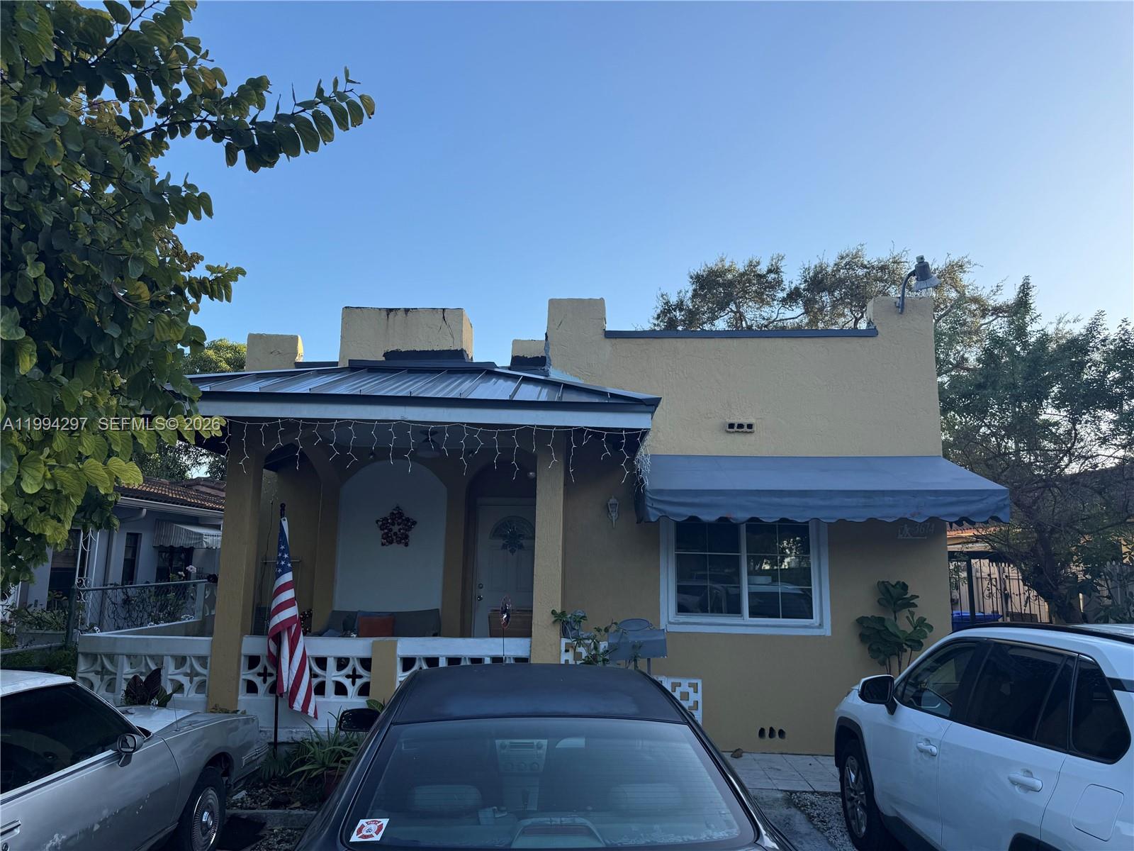 A single-story yellow stucco house features a covered front porch and a metal awning — 3674 SW 25th St, Miami FL 33133, MIAMI, FL