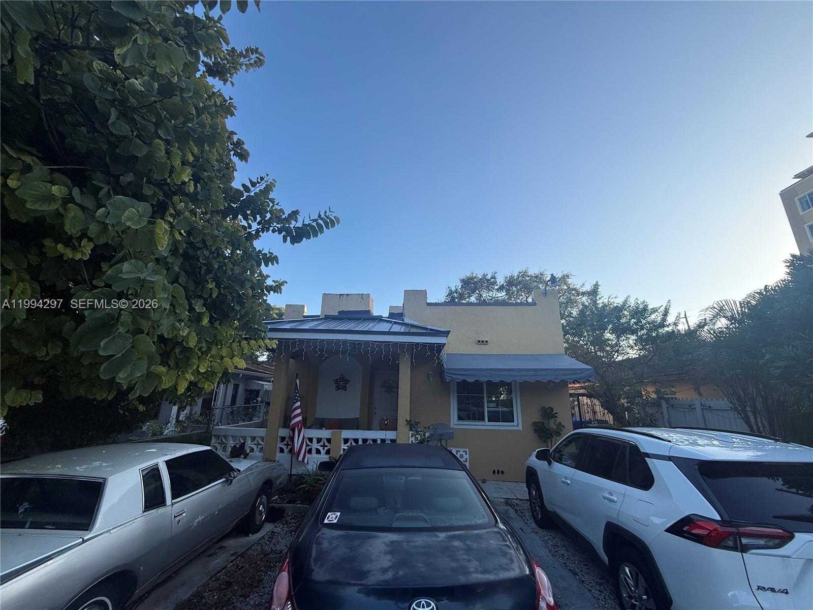 A yellow single-story house with a front porch and three cars parked in the driveway — 3674 SW 25th St, Miami FL 33133, MIAMI, FL