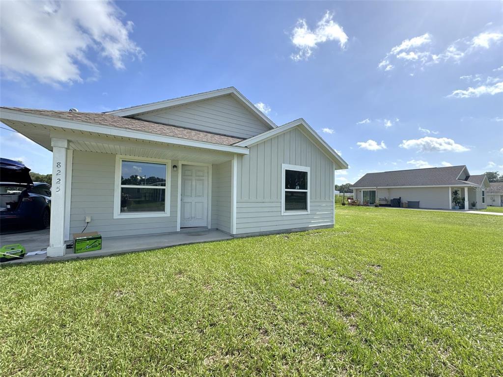 A light gray single-story house with a covered front porch and a large grassy yard — 8225 E ROSKO COURT, FLORAL CITY, FL