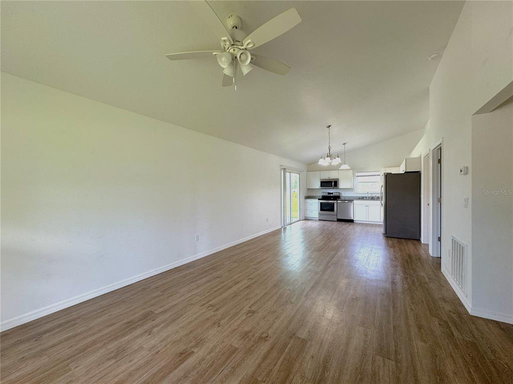 An open-concept living area features wood-look flooring, a ceiling fan, and an adjacent kitchen — 8225 E ROSKO COURT, FLORAL CITY, FL