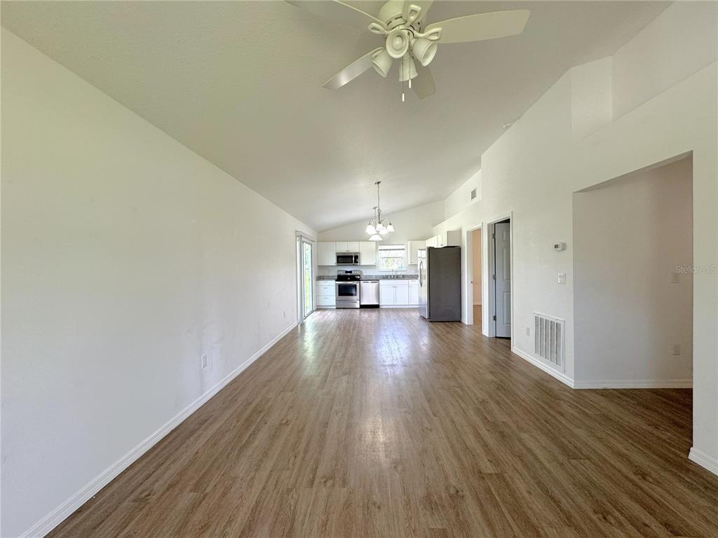 An open-concept living area features wood-look flooring, a ceiling fan, and a kitchen with white cabinets — 8225 E ROSKO COURT, FLORAL CITY, FL