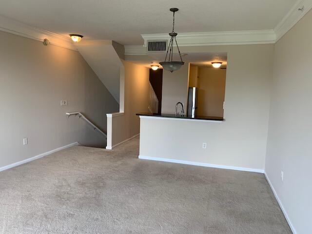 An open living area features beige carpet, a staircase, and a kitchen with a breakfast bar — 2058 Alta Meadows Lane # 2503, Delray Beach FL 33444, DELRAY BEACH, FL