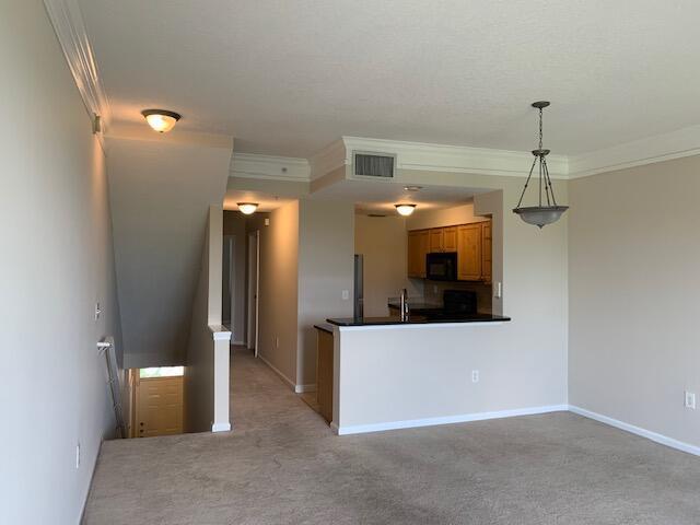 An interior view shows a carpeted living area, a kitchen with wood cabinets, and stairs — 2058 Alta Meadows Lane # 2503, Delray Beach FL 33444, DELRAY BEACH, FL