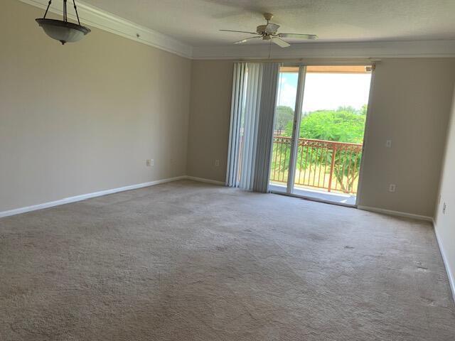 An empty living room with beige carpet, a ceiling fan, and a sliding glass door — 2058 Alta Meadows Lane # 2503, Delray Beach FL 33444, DELRAY BEACH, FL