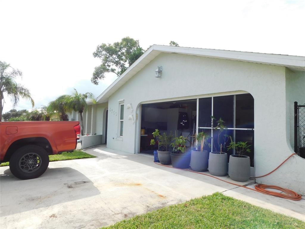 A single-story house exterior features a garage with a screen door and potted plants — 8750 SW LIVERPOOL ROAD, ARCADIA, FL