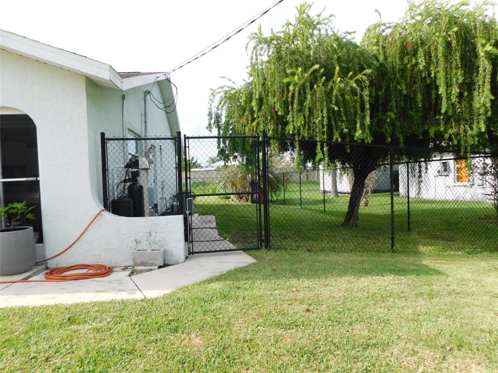 A black chain-link fence and gate enclose a grassy backyard next to a house — 8750 SW LIVERPOOL ROAD, ARCADIA, FL
