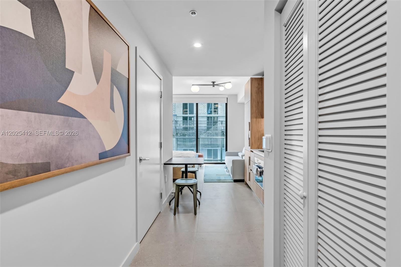 A narrow hallway leads into a studio apartment with a kitchenette, dining area, and balcony — 11 NE 6th St # 2608, Miami FL 33132, MIAMI, FL